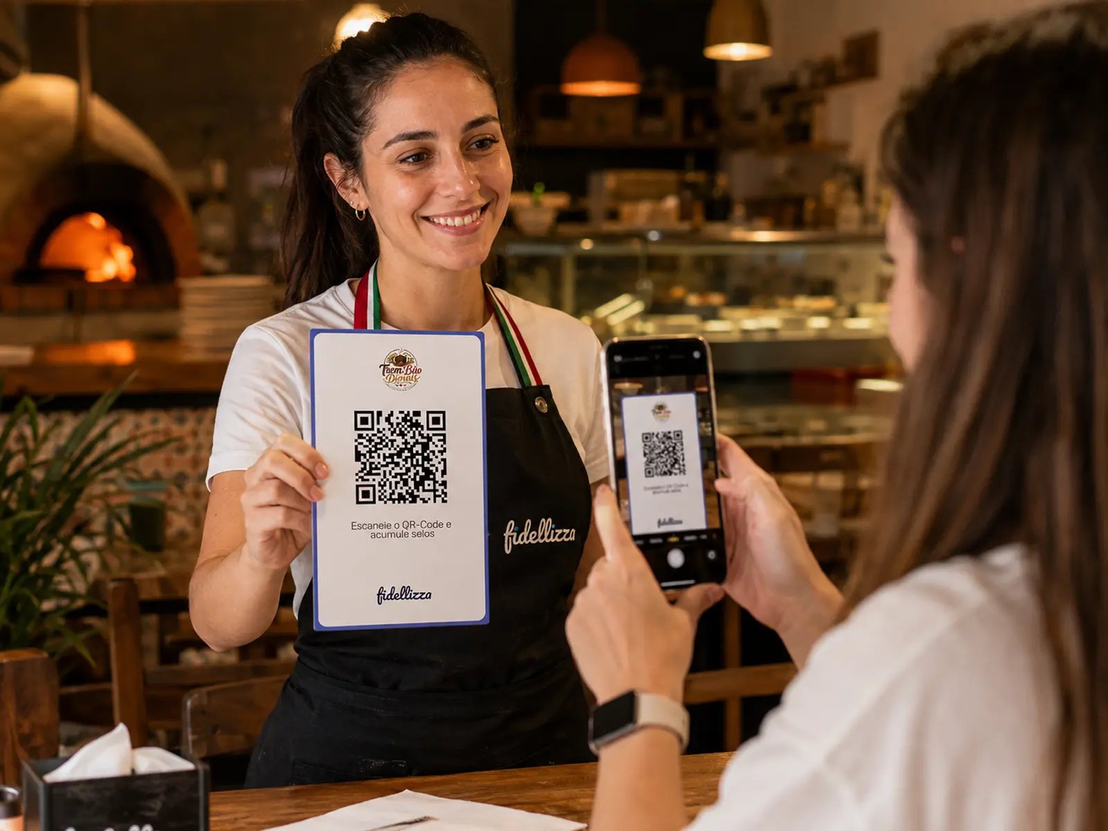 Atendente mostrando o cartaz com QR Code e cliente escaneando com o celular